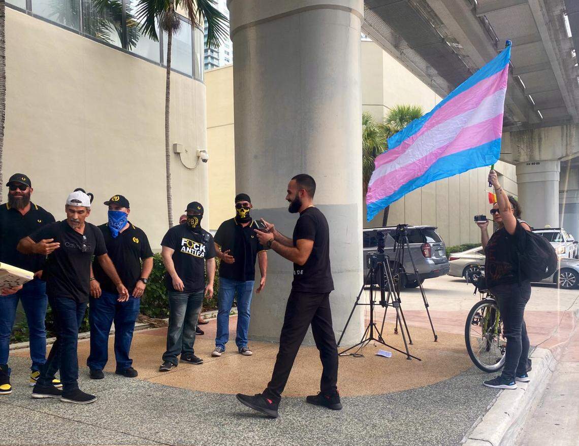 A person waving a transgender flag stands in front of a group of Proud Boys outside a contentious Miami-Dade School Board meeting in September 2022, where the board voted 8-1 against recognizing October as LGBTQ month. In 2021, the board had voted 7-1 to recognize the designation.