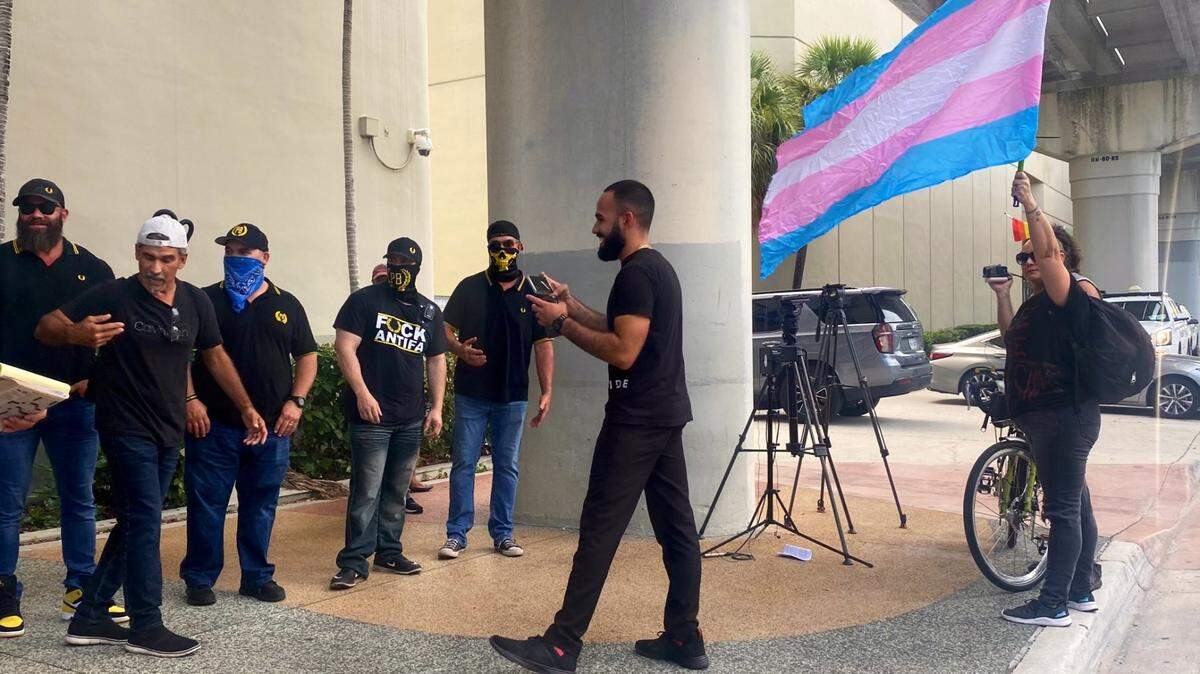 Una persona hace ondear una bandera transgénero frente a un grupo de Proud Boys afuera de una polémica reunión de la Junta Escolar de Miami-Dade en septiembre de 2022, donde se discutió el reconocimiento del Mes de la Historia LGBTQ+.