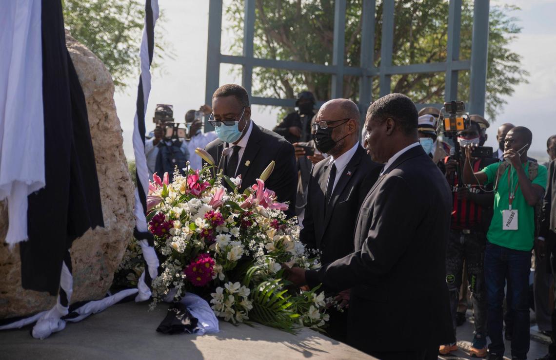 Haitian Prime Minister Ariel Henry, center, places a bouquet of flowers at a monument in memory of the victims of the 2010 earthquake at Titanyen north of Port-au-Prince, Haiti, Wednesday, Jan. 12, 2022.