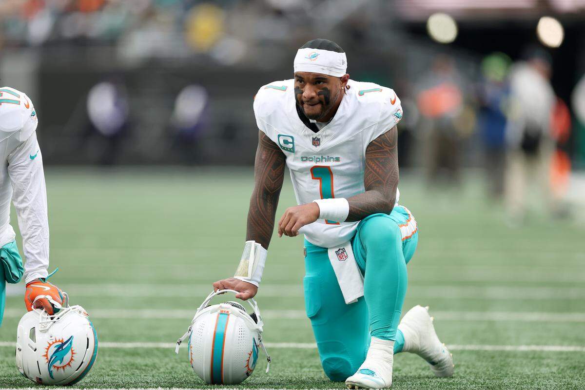 EAST RUTHERFORD, NEW JERSEY - DECEMBER 07: Tua Tagovailoa #1 of the Miami Dolphins kneels for an injured New York Jets player during the first quarter at MetLife Stadium on December 07, 2025 in East Rutherford, New Jersey. (Photo by Kenneth Richmond/Getty Images)