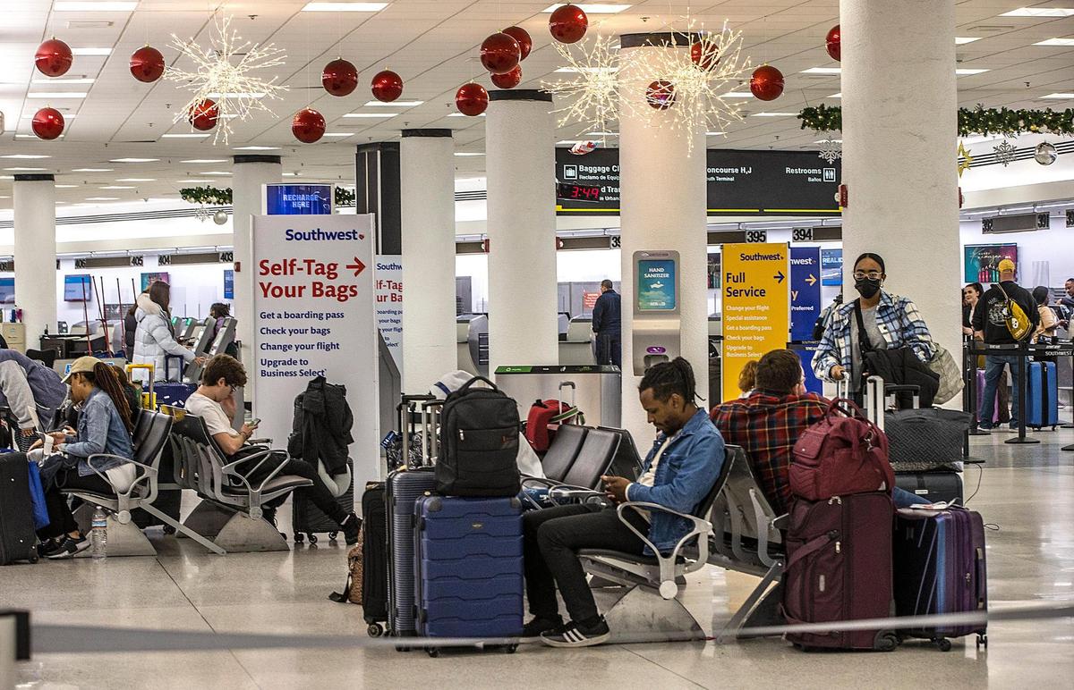 In this file photo from Dec. 27, 2022, passengers seated at the Southwest Airlines counters areas at Miami International Airport check flight status and ponder options. On that day, Southwest canceled more than 60% of its flights due to bad winter weather elsewhere across the U.S.