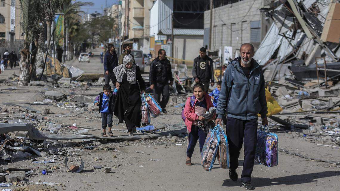 Palestinians walk with their belongings amid the devastation caused by the Israeli bombing on the Nuseirat refugee camp in the Gaza strip on Jan. 18.