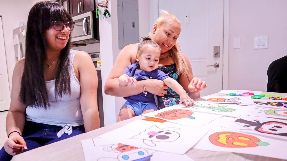 Wilangelys Porrata, left, shares some of her older drawings with her mother, Angelica Rodriguez, and her 1-year-old brother, JJ, in their North Miami apartment. Wilangelys stopped drawing three years ago when a genetic condition caused her vision to deteriorate steadily, to the point that she could no longer see the outlines of her work. Now she’s drawing again.