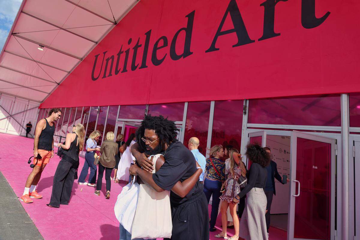 Miami Beach, FL, December 2, 2025 - Artist embrace as they exit Untitled Art on opening day.
