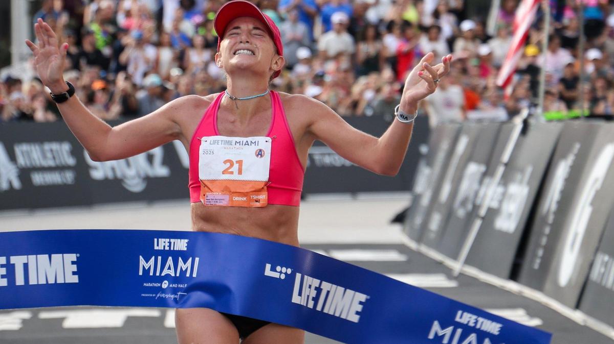 Marathon runner Beth Marzigliano lifts her arms in victory as the first woman to complete the marathon as over 18,000 athletes and runners participated in the 2025 Life Time Miami Marathon and Half on February 2, 2024, in downtown Miami, Florida.