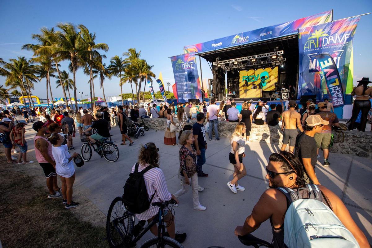 People walk by a concert for Art on the Drive, a Carnaval Miami event, at Lummus Park during Spring Break in Miami Beach, Florida, on Saturday, March 18, 2023.