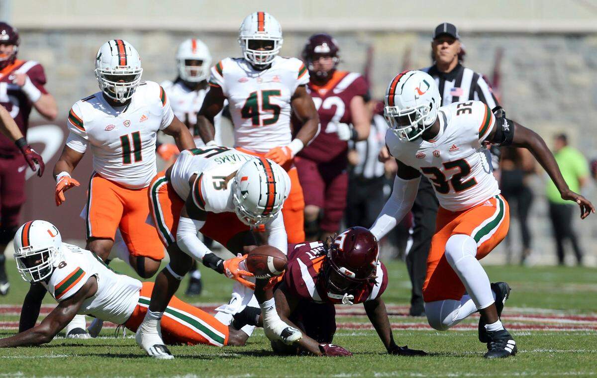 Miami’s Avantae Williams (15) scoops up a fumble by Virginia Tech’s Dae’Quan Wright (13) in the first half during the first half during the first half of an NCAA football game, Saturday Oct. 15 2022, in Blacksburg Va. (Matt Gentry/The Roanoke Times via AP)