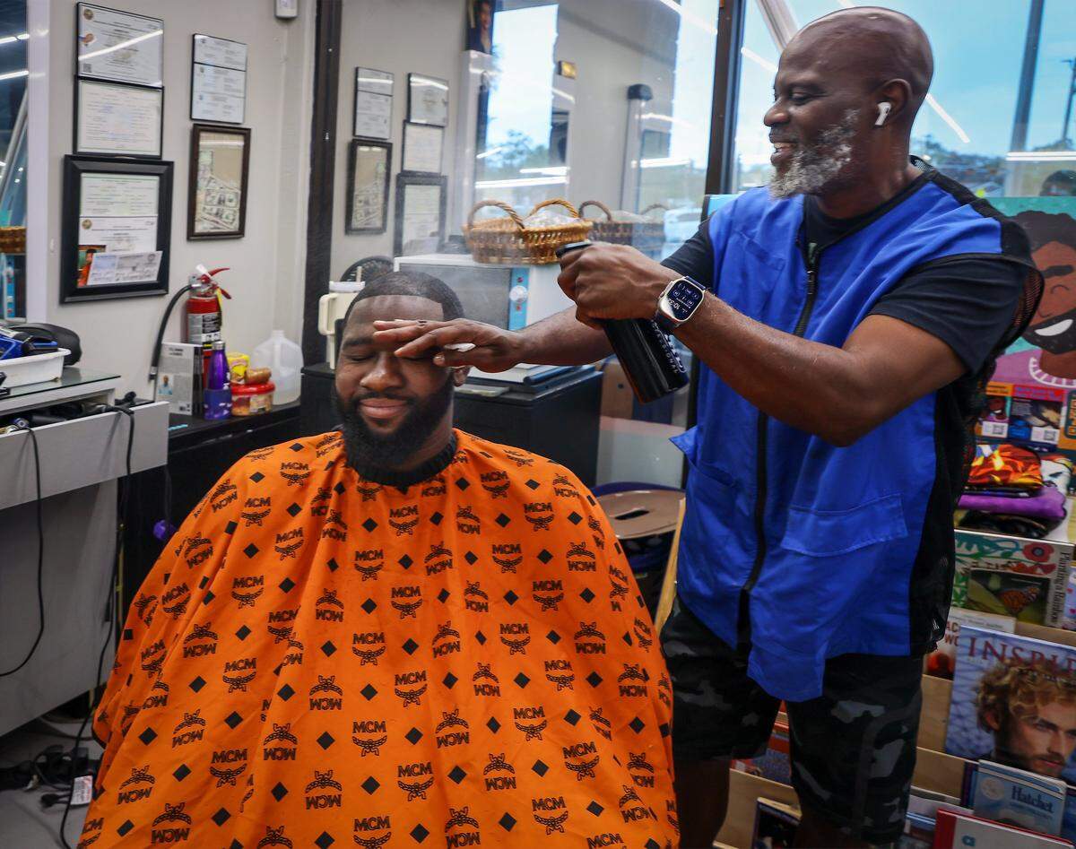 Topcuttaz in Miami Gardens often hosts meetings where Black men come together to discuss important topics. Here owner Mike Stephens, right, gives the final touch after cutting the hair of Jefferson Noel, 31, left, founder of Barbershop Speaks, which hosts the discussions. 