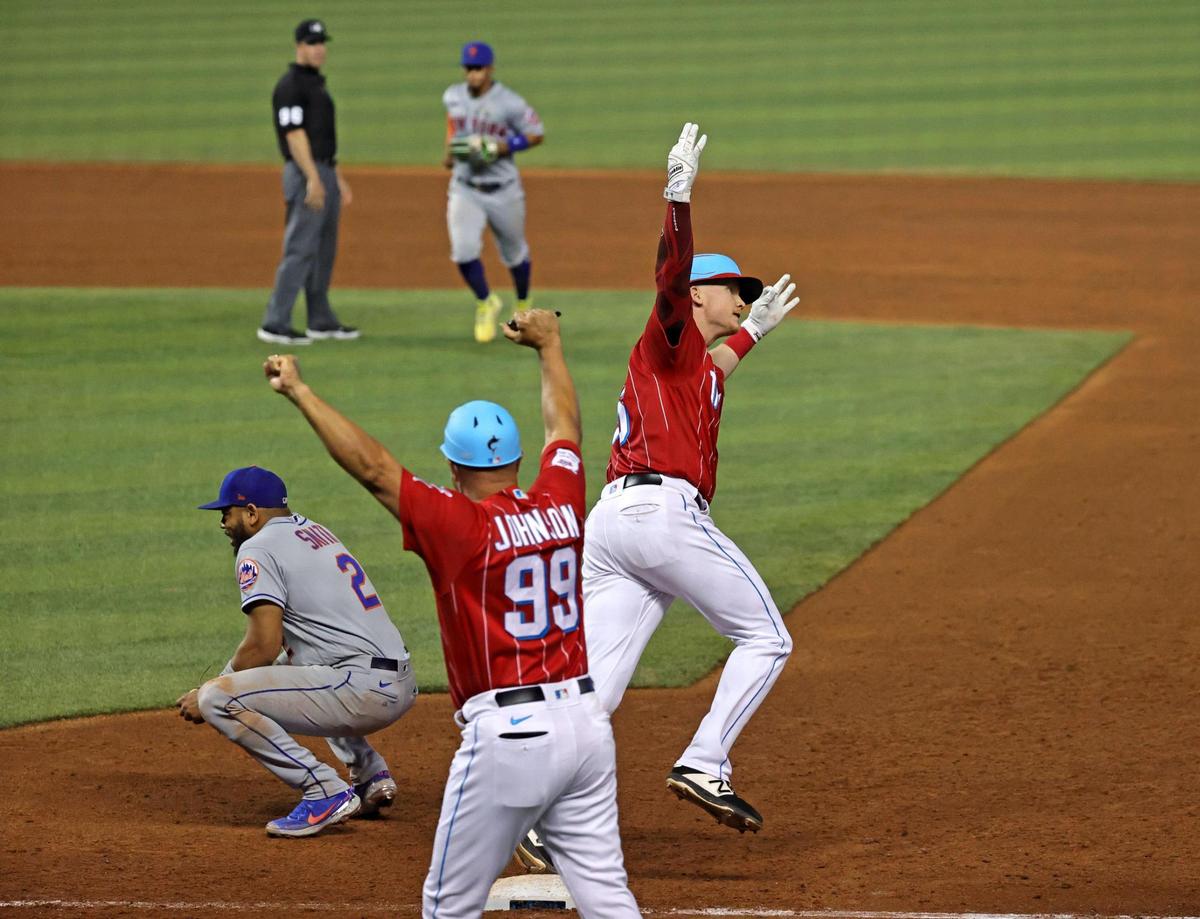 New York Mets first baseman Dominic Smith (2) reacts as Miami Marlins right fielder Garrett Cooper (26) is congratulated by Marlins first base coach Keith Johnson (99) after hitting a walk-off two run Mets pitcher against Drew Smith (62) during the ninth inning of their baseball game at loanDepot park on Saturday, May 22, 2021 in Miami, Florida.