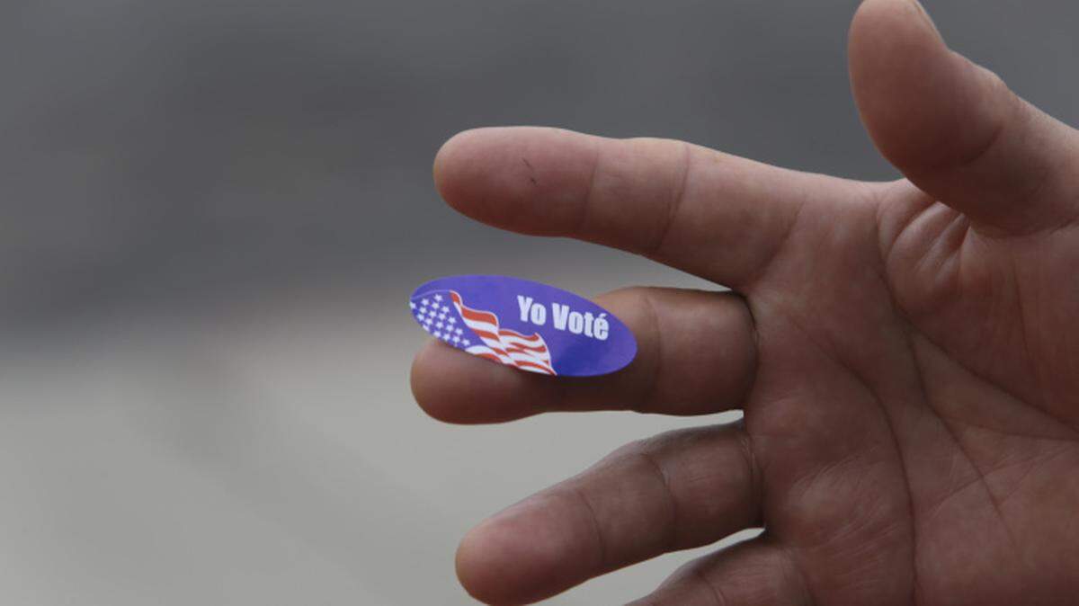 A voter displays a Spanish-language sticker during elections.