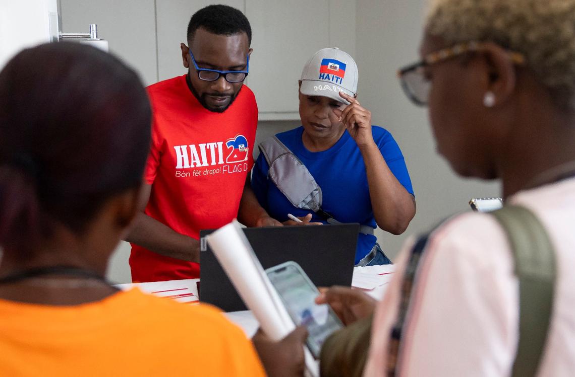 Sammy Lamy, the director of Jobs For Us, and Claudya Gebara, a volunteer, help people register for a community resource fair at the Magic City Innovation District on Friday, May 31, 2024, in Miami, Fla. The fair aimed at helping recently arrived Haitians and other immigrants connect with health care providers and prospective employers.