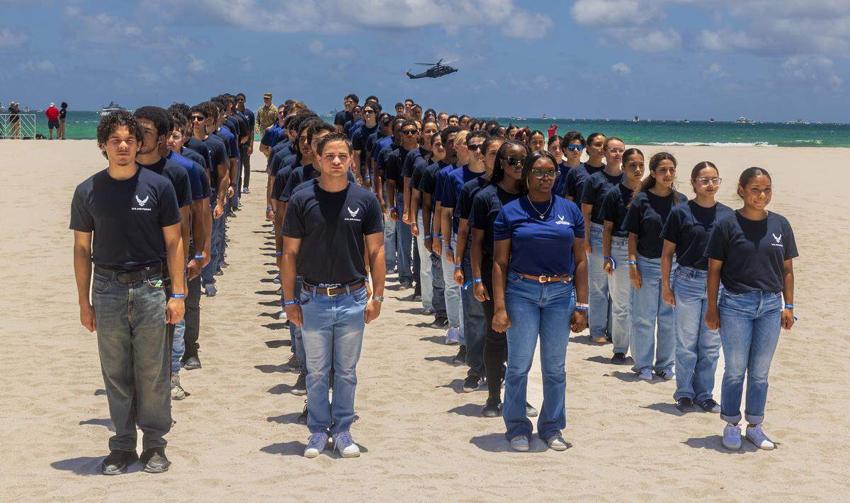 A helicopter flies over as group of future military members lined up at a special Enlistment Swearing-In Ceremony honoring the next generation of American service members in South Beach during the Hyundai Air & Sea Show annual National returns Salute to America's Heroes for Memorial Day Weekend celebration, in Miami Beach, on Saturday, May 23, 2026.