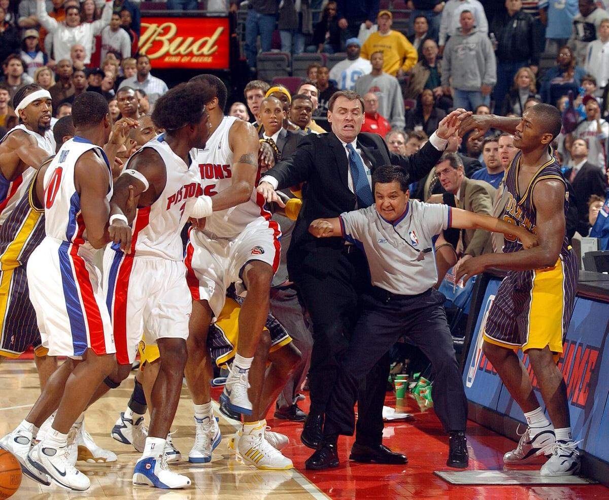 Ben Wallace of the Detroit Pistons and teammates are kept apart from Ron Artest of the Indiana Pacers by Pacers head coach Rick Carlisle and official Tommy Nunez Jr 19 November 2004 during their game at the Palace of Auburn Hills in Auburn Hills, Michigan.