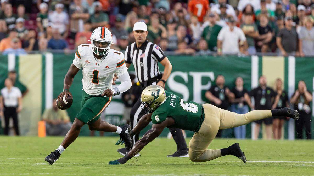 Miami Hurricanes quarterback Cam Ward (1) runs with the ball as South Florida Bulls linebacker Jamie Pettway (6) fails to stop him in the first half of their NCAA college football game at the Raymond James Stadium on Saturday, Sept. 21, 2024, in Tampa, Fla.