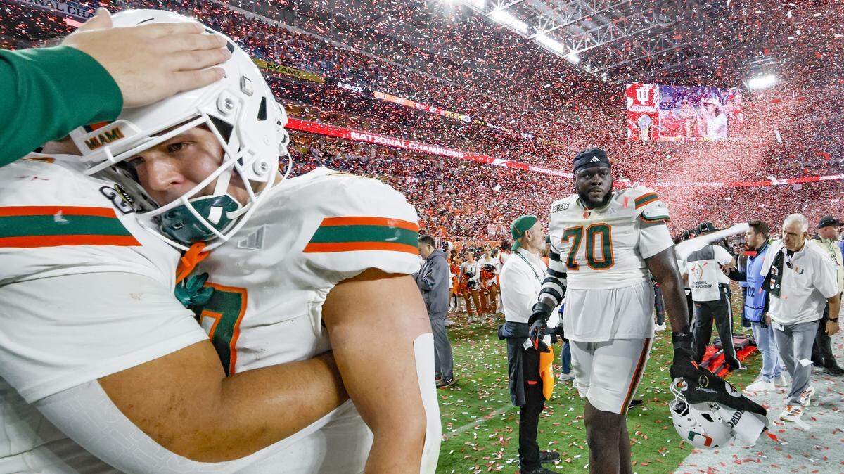 Miami Hurricanes tight end Alex Bauman (87) is consoled as offensive lineman Markel Bell (70) walks off the field after the Indiana Hoosiers defeat the Canes in the College Football Playoff National Championship Game at Hard Rock Stadium in Miami Gardens, Florida, on Monday, January 19, 2026.
