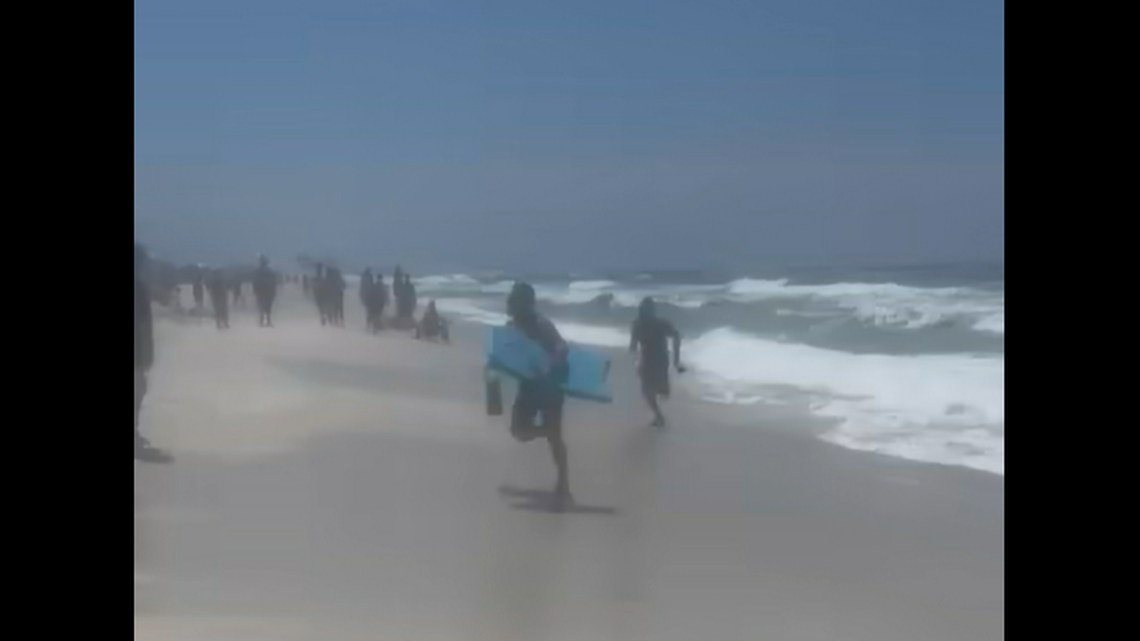 The suspect came ashore after 25 minutes and tried to outrun deputies through “the large crowd that had gathered to watch,” officials said.