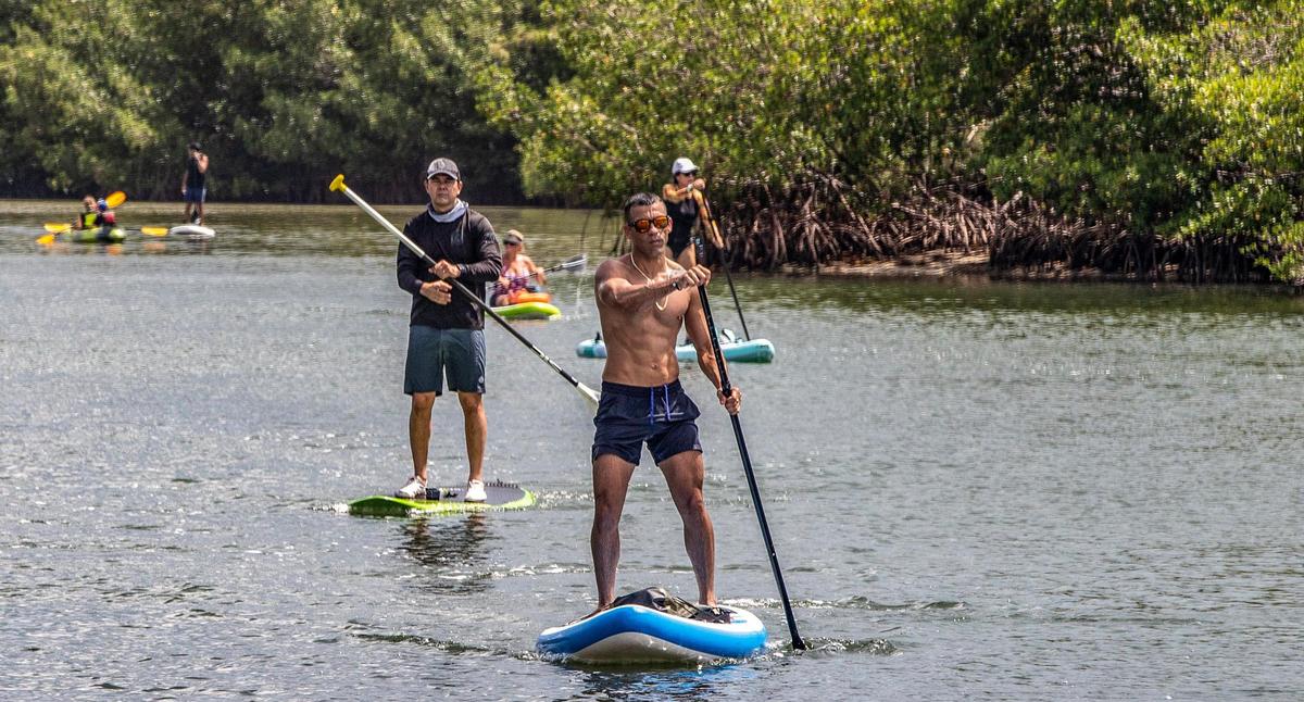 Un grupo de entusiastas de las actividades al aire libre, incluido el comisionado de la Ciudad de Miami, Ken Russell (extrema izquierda), se lanzó al agua en tablas de remo y kayaks en Virginia Key para protestar contra los planes de construir casas pequeñas en el cayo para personas sin hogar, el sábado 6 de agosto de 2022.
