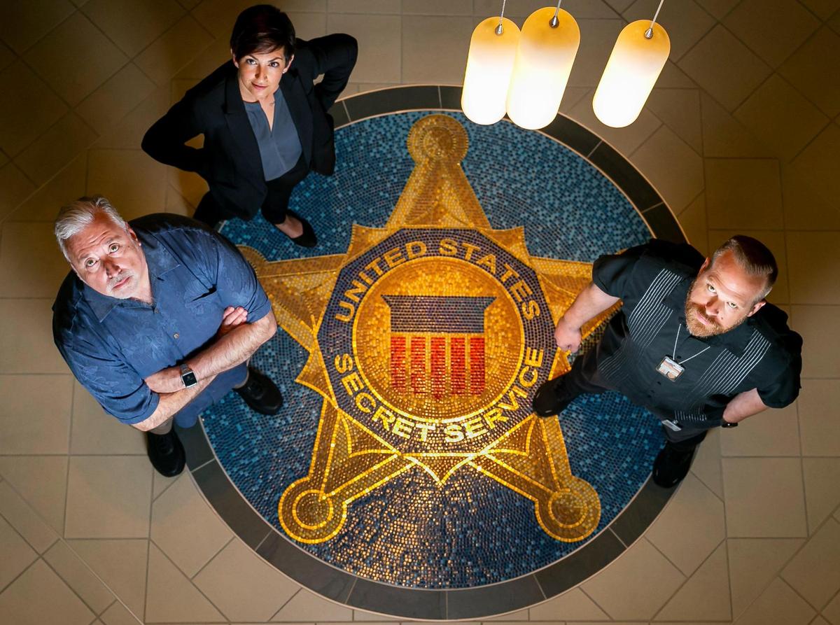 From left, Miami-Dade Police Maj. George Perera, Sgt. Bridget Doyle and Lt. Jordan Fried around the logo for the South Florida Cyber Crimes Task Force.