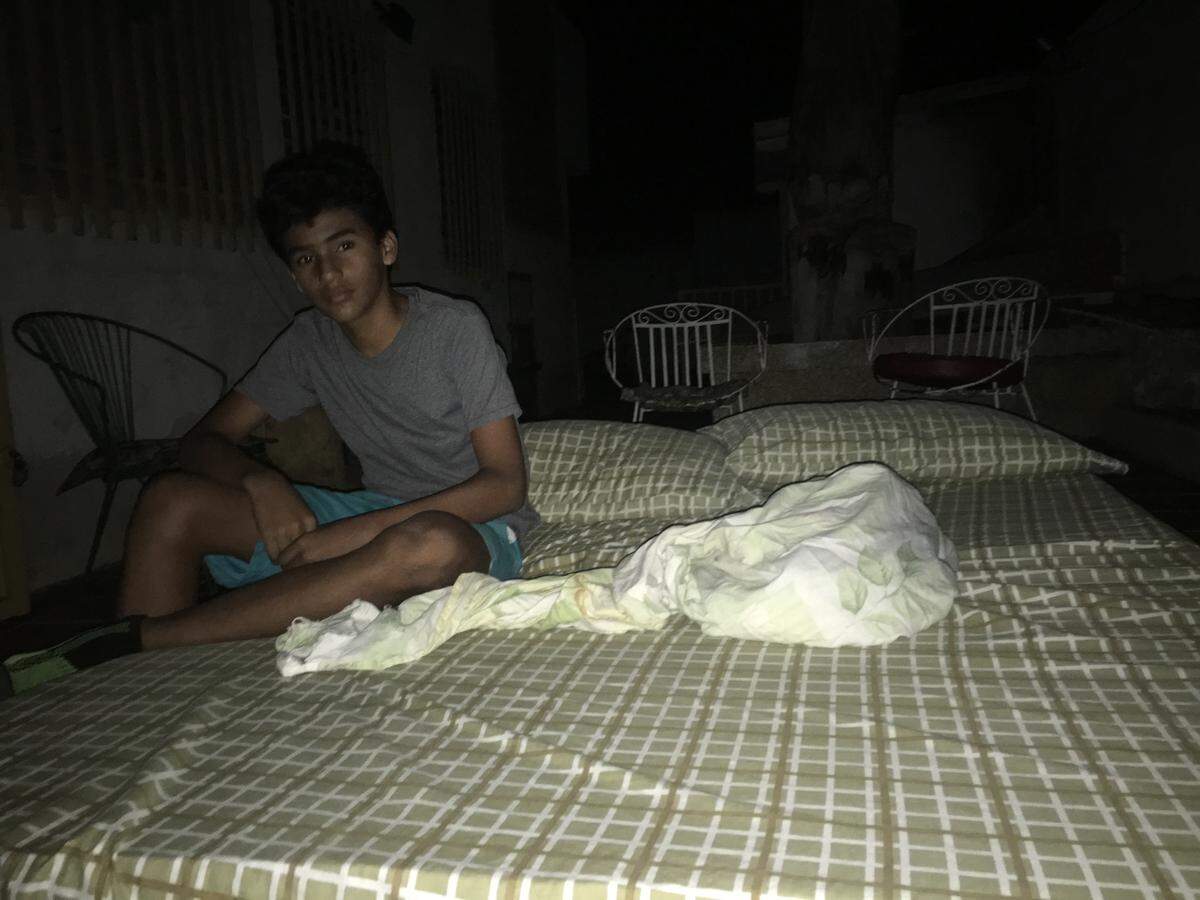 Luis Ignacio, 12, sitting in the dark in his backyard.