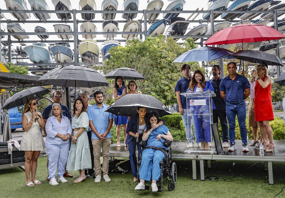 Boating accident survivor, Katerina “Katy” Puig, front and center, kisses her sister's hand. Amanda Puig, as Meli Fernandez, the mom of boating accident victim, Luciana “Lucy” Fernandez, speaks during a press conference commemorating the signing of Lucy's Law at Bayshore Club in Miami, Florida, on Wednesday, July 2, 2025. The signing of Lucy's Law spotlight's “Have Fun. Be Safe.” campaign ahead of the July 4th holiday weekend-one of the busiest and most dangerous periods on Florida's waterways. Lucy's Law, signed into law on June 27, 2025, and effective July 1, 2025, honors the life of 17-year-old Luciana Fernandez.