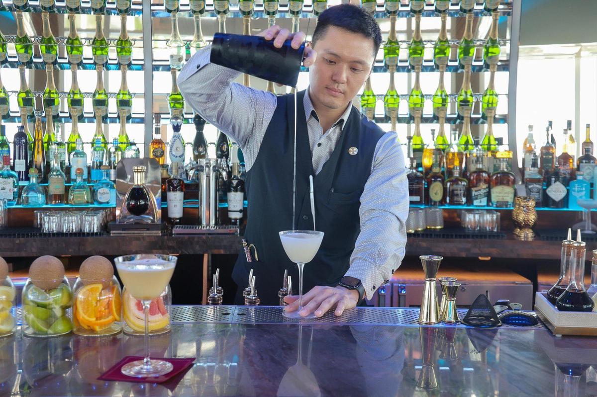 Bartender Daniel Kan creates the Tango on Top cocktail at Pier Top with Amaro Nonino and Strega, two Italian herbal liqueurs; prosecco; pineapple juice and matcha coconut tea.