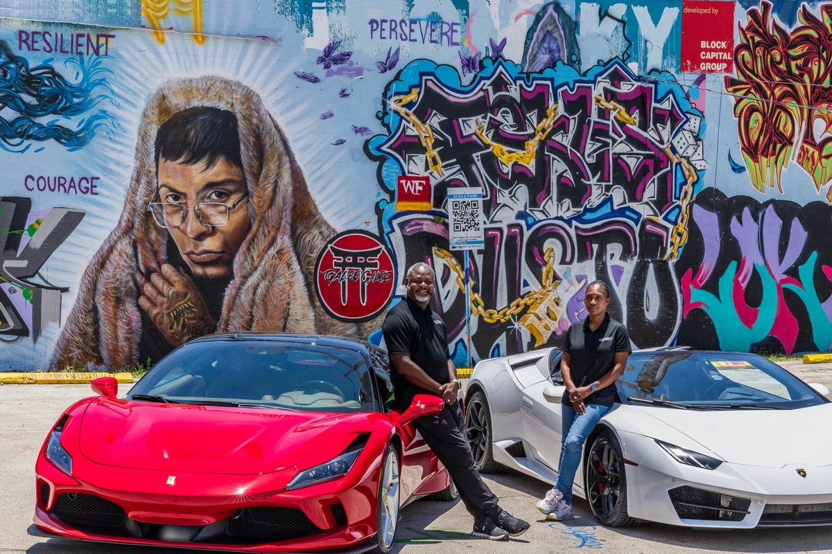 CEO/Founders Marlon and Jessica Wentworth pose next to two luxury vehicles in Wynwood, a red Ferrari F8 Tribute and a white Lamborghini Huracan, from their fleet of exotic cars at Energetic Exotics, a luxury car rental and concierge business, on Friday, July 05, 2024.