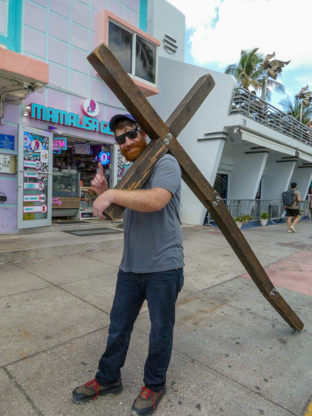 Wade Aaron, 35, walked along Ocean Drive, lugging a large, wooden cross over his shoulder, while visiting Miami Beach during spring break on Sunday, March 10, 2024.