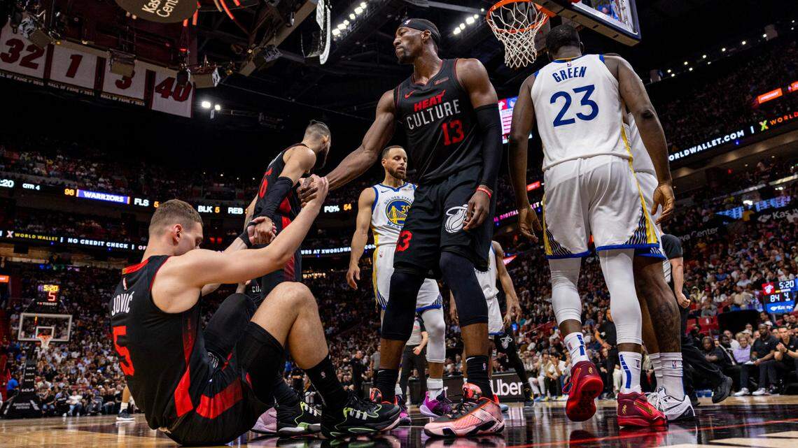 Miami Heat center Bam Adebayo (13) helps up teammate Nikola Jovic (5) during the second half of an NBA game against the Miami Heat at Kaseya Center in Miami, Florida, on Tuesday, March 26, 2024.