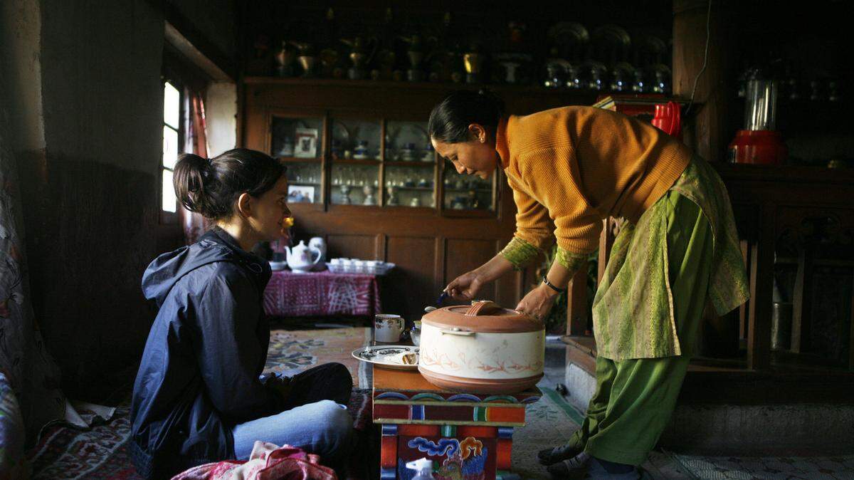 In this picture taken 21 July 2007, Swedish actress Melinda Kinnaman (L) is served breakfast by her homestay host Padma Dolma in the village of Rumbak, some 30kms south east of Leh.