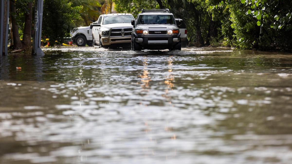 Vehículos circulan por una calle inundada cerca del Little River Pocket Park el 30 de octubre de 2023, en Miami, Florida. El lunes fue la marea reina más alta del año en el sur de la Florida, inundando calles, accesos vehiculares de casas y parques.