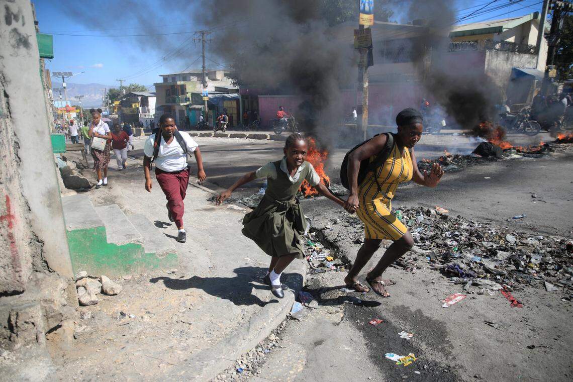 A woman with her daughter walks past a barricade that was set up by members of the police as they protest bad police governance, in Port-au-Prince, Haiti, Thursday, Jan. 26, 2023.