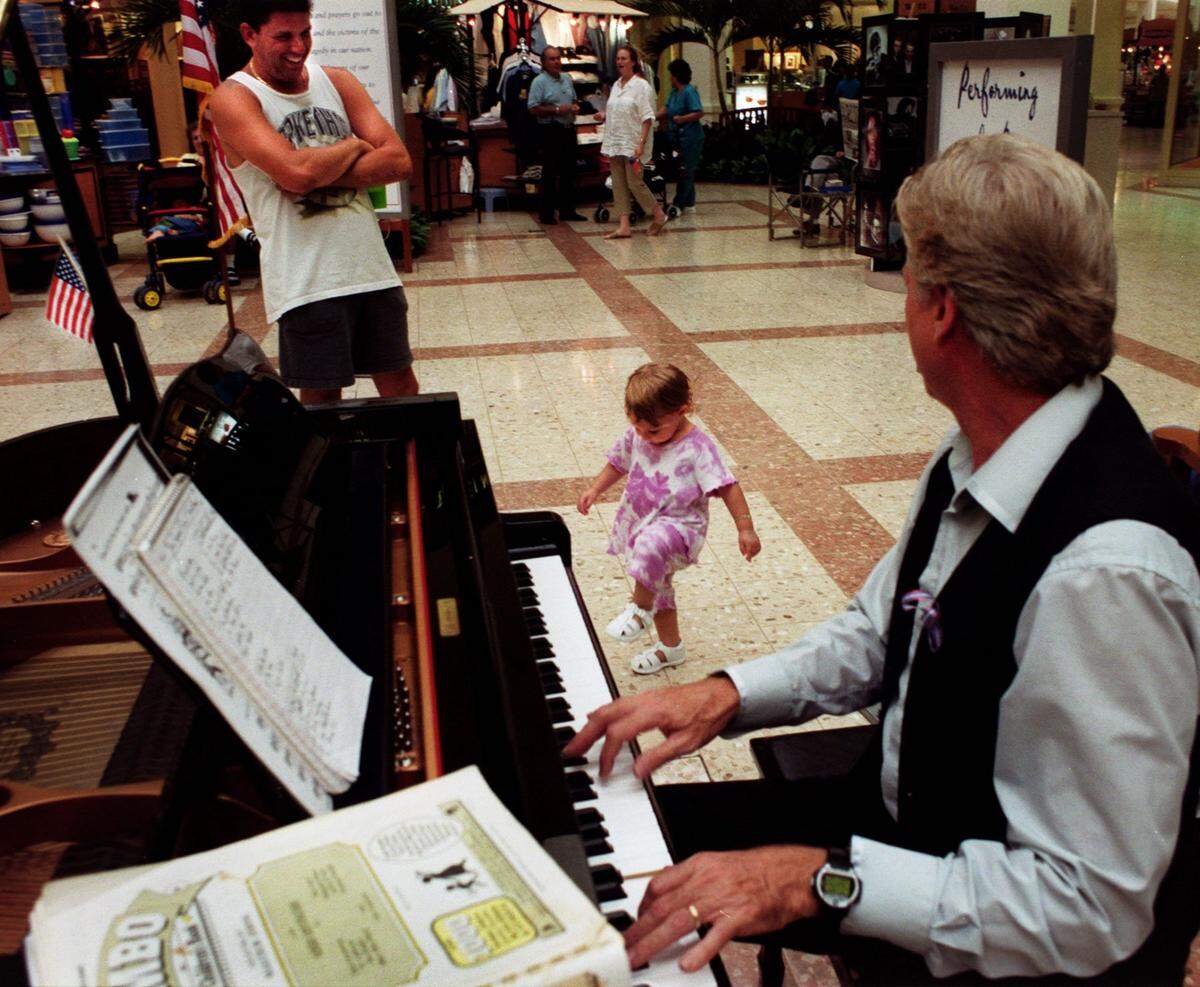 Thursday 09/13/01 - Richard Patterson/for the Herald - From Left: Dean Shechtman, of Aventura, watches his daughter, Taylor Shechtman, 20 months, dance to some oldies that were being played by Mel Olman, of Hollywood and a piano player in the Aventura mall for 6 years inside of the mall. 3 of 3