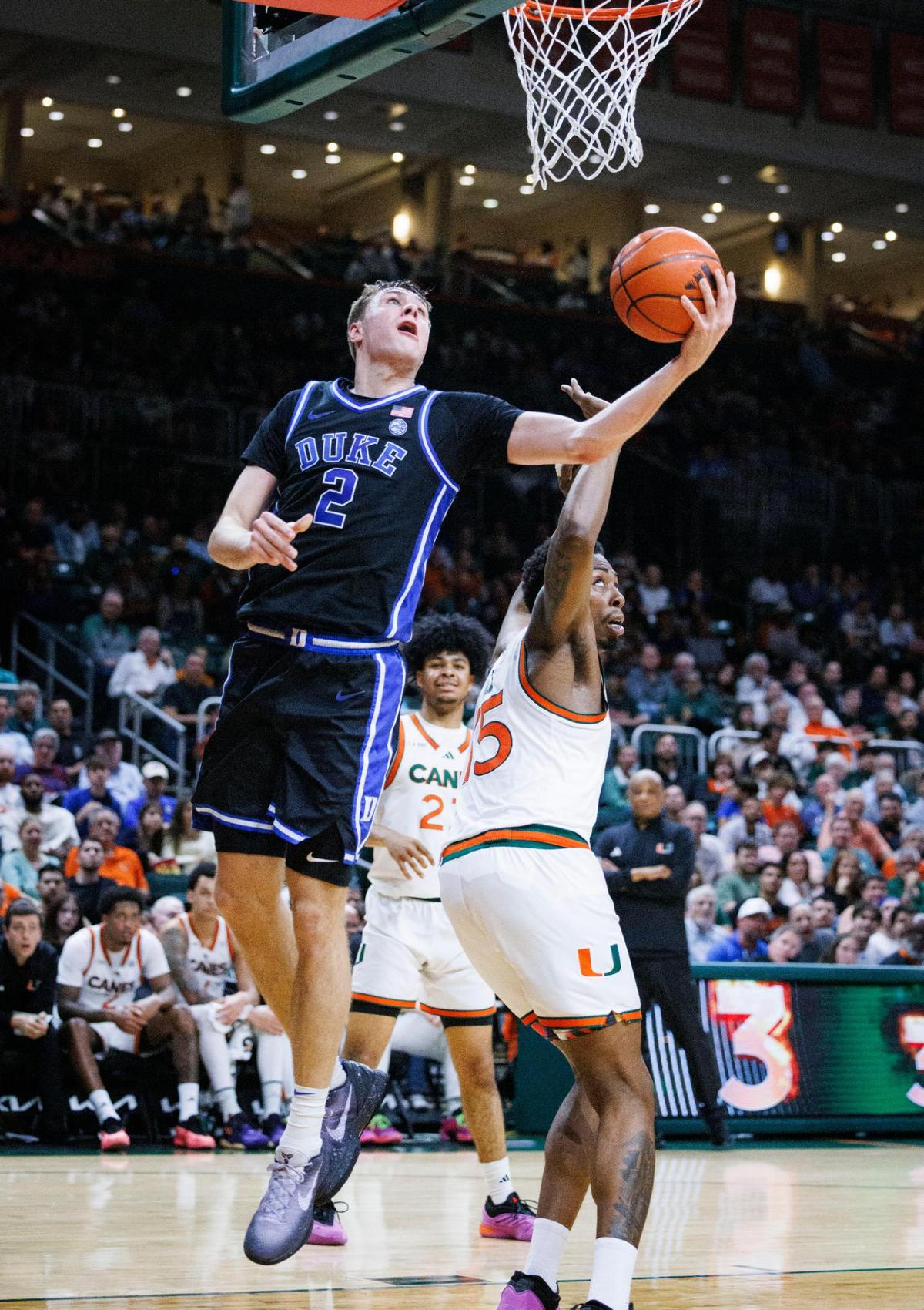 Duke Blue Devils guard Cooper Flagg (2) shoots a layup around Miami (Fl) Hurricanes forward Kiree Huie (15) during the first half of a game on Tuesday, Feb. 25, 2025, at Watsco Center in Coral Gables, Fla.