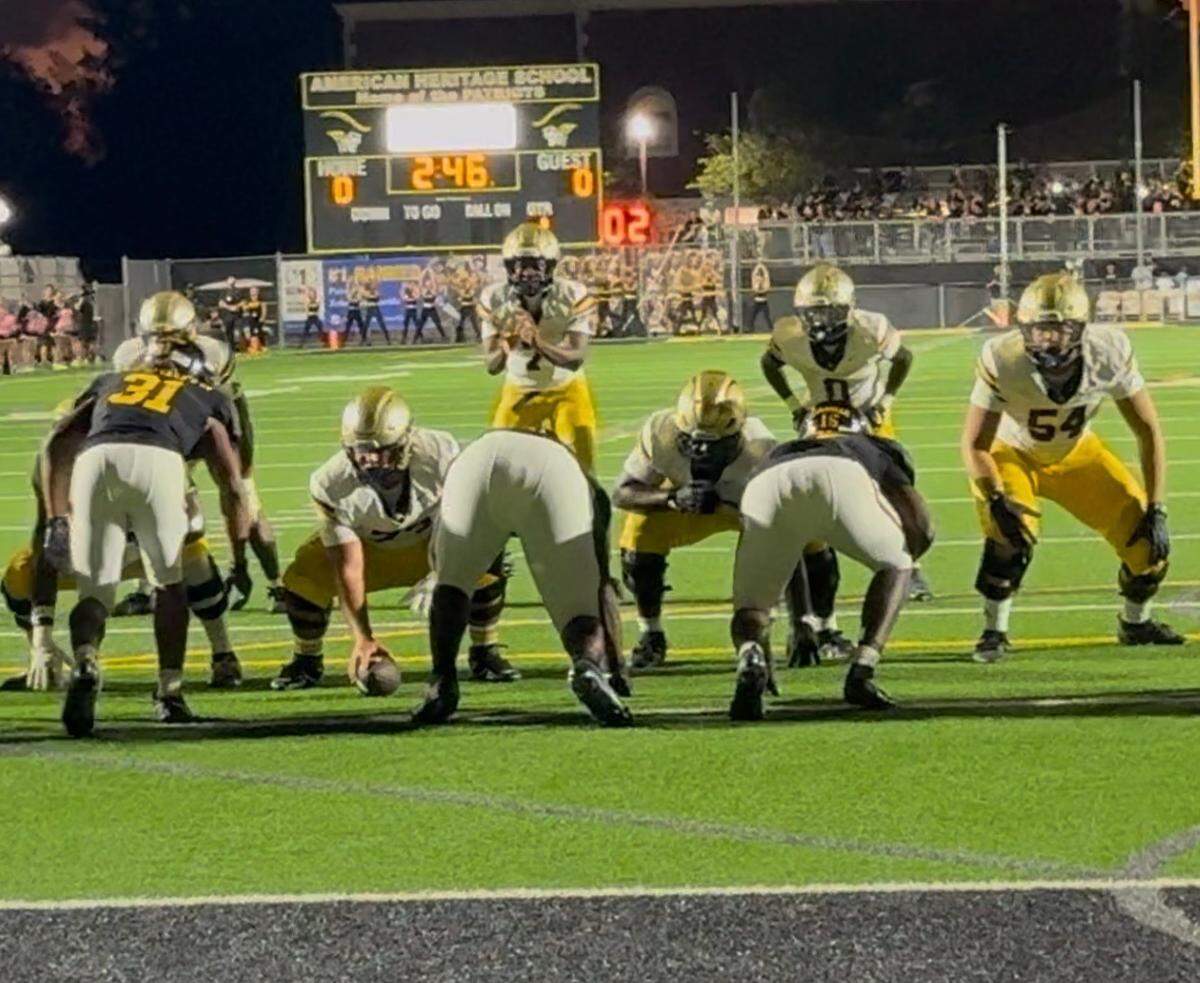 St. Thomas Aquinas quarterback Mason Mallary prepares to take a snap during the Raiders’ game against American Heritage on Friday night at Heritage;s home field in Plantation, Fla.