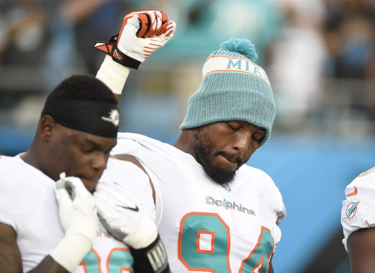 Miami Dolphins’ Robert Quinn (94) raises his fist during the national anthem before a preseason NFL football game against the Carolina Panthers in Charlotte, N.C., Friday, Aug. 17, 2018. (AP Photo/Mike McCarn)
