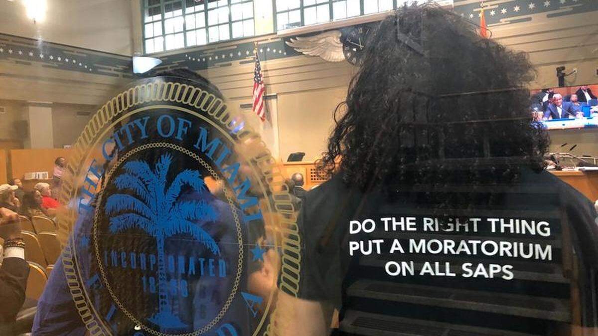 Protesters against the Magic City Special Area Plan in Little Haiti stand inside Miami Commission chambers during the final hearing.