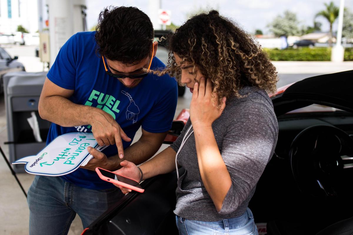 Brand ambassador Gerardo Arellano explains to FIU student Andreina Yoria about the app GetUpside at the Shell Gas Station located in 10690 SW 8th Street which is part of the GetUpside promotion giving 750 drivers in Miami $20 worth of gas cupon on Wednesday February 12, 2020.