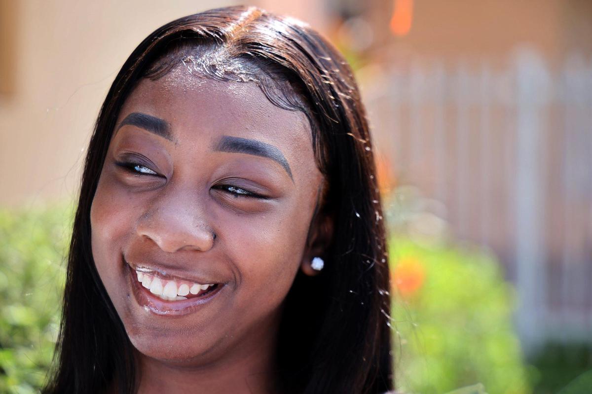 Graduating senior at Booker T. Washington High Zamiah Wadley, center, smiles after receiving a surprised scholarship from the Biscayne Bay Kiwanis Club to attend college at Bethune-Cookman University.