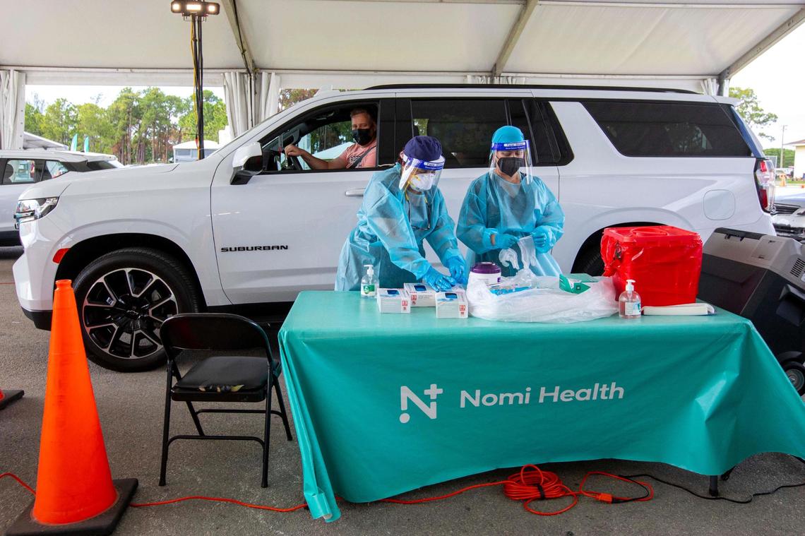 A motorist sits in his vehicle as he waits for a healthcare professional to swab his nose for a COVID-19 PCR Nasal Swab test at a Nomi Health testing center inside Tropical Park in Miami, Florida, on Tuesday, May 24, 2022.