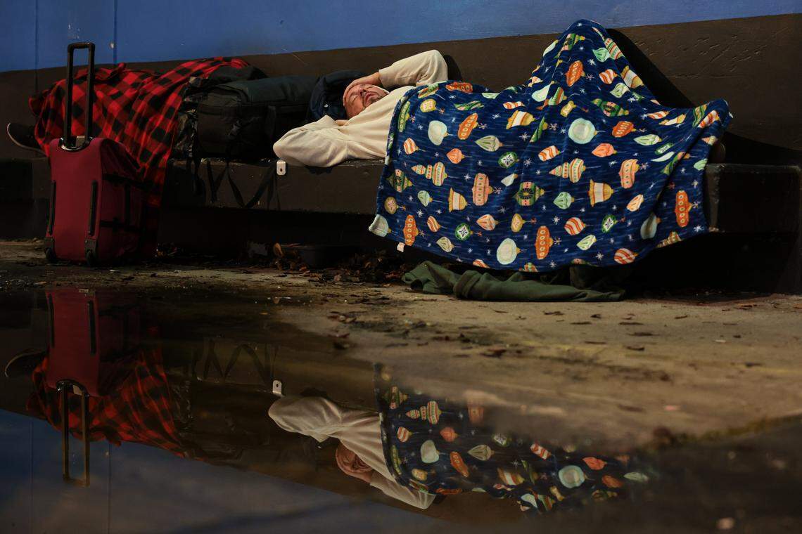 A man experiencing homelessness sleeps on a concrete bench along Northwest Third Street during the Homeless Trust's biannual Homeless Census in downtown Miami on Thursday, Jan. 22, 2026.
