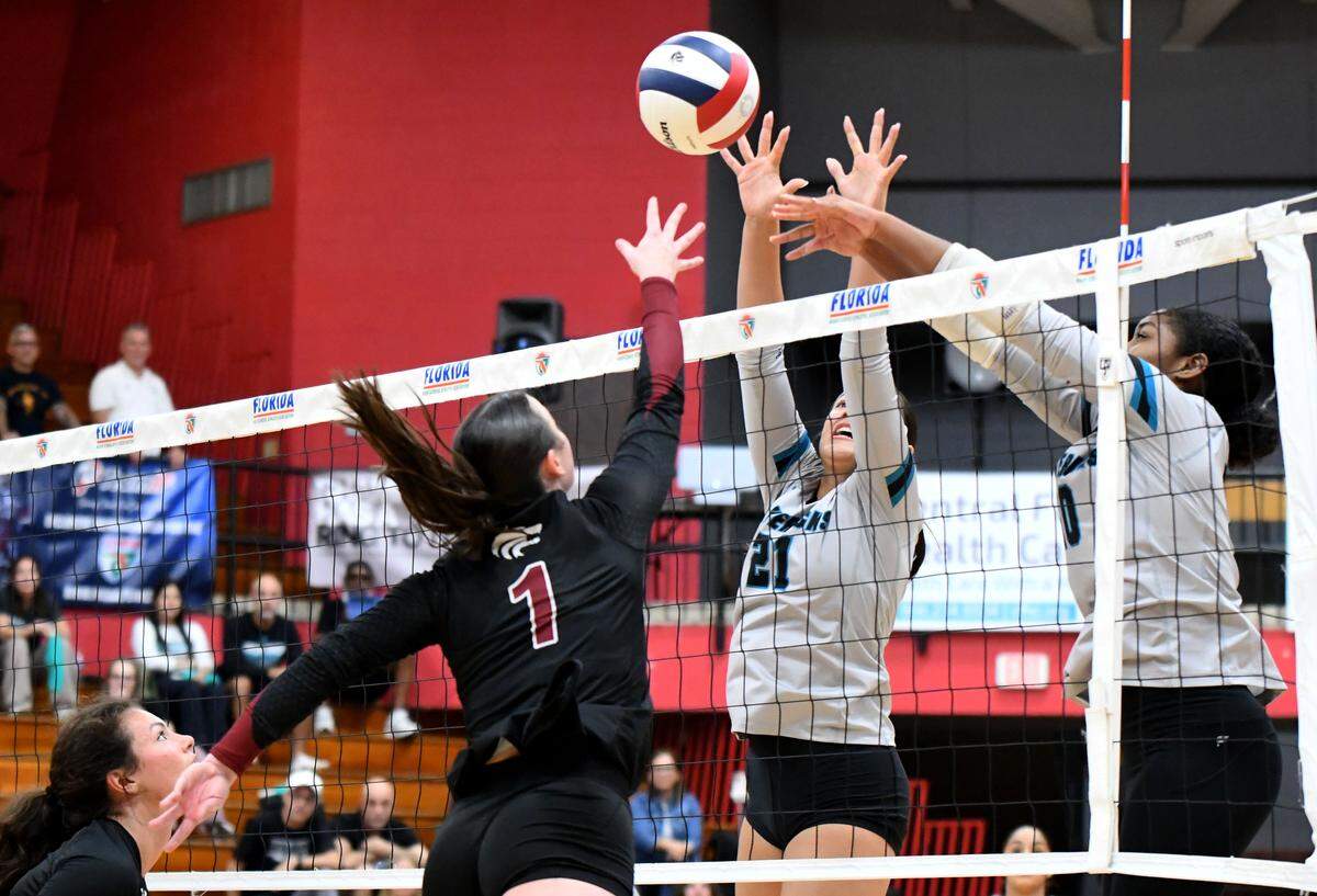 Archbishop McCarthy front-line players Valentina Santamaria (21) and Em’Pris Seetal (10) block a shot from Tallahassee Chiles senior Eva Goodson (1) during the Class 5A girls volleyball state championship game on Saturday at Polk State College in Winter Haven.