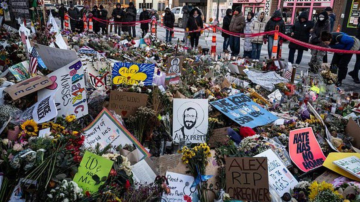 People visit the makeshift memorial for Alex Pretti set up in the area where he was recently shot and killed by federal immigration agents in Minneapolis, Minnesota, on January 29, 2026. US President Donald Trump's border chief Tom Homan said on January 29 that some federal agents could be withdrawn from Minneapolis, the northern US city that has become the flashpoint for the president's immigration crackdown. The Trump administration, facing a public backlash over the shooting deaths of two Americans by federal agents in Minneapolis, also eased immigration operations in the northeastern state of Maine. (Photo by ROBERTO SCHMIDT / AFP via Getty Images)