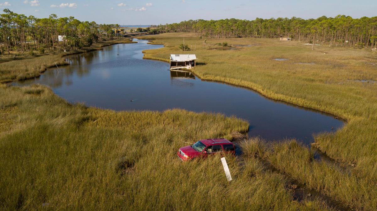 A red vehicle that belonged to a Simmons Bayou, Florida, man named Bill McConnell sits in a muddy lake behind his former home. Bill, his neighbors said, was killed trying to escape Hurricane Michael. His body was recovered days later near the truck.