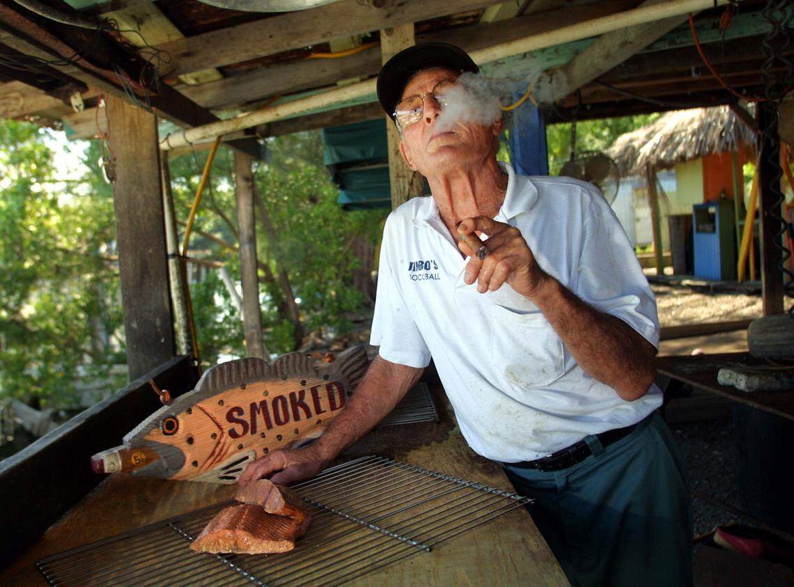 In 2003, Jim Luznar Sr., owner of Jimbo’s, a Virginia Key institution that offers cold beverages and smoked fish, savors a stogie at the outdoor table where he cuts and trims fish before it’s smoked on the premises. A sampling of Luznar’s smoked salmon, foreground, and smoked