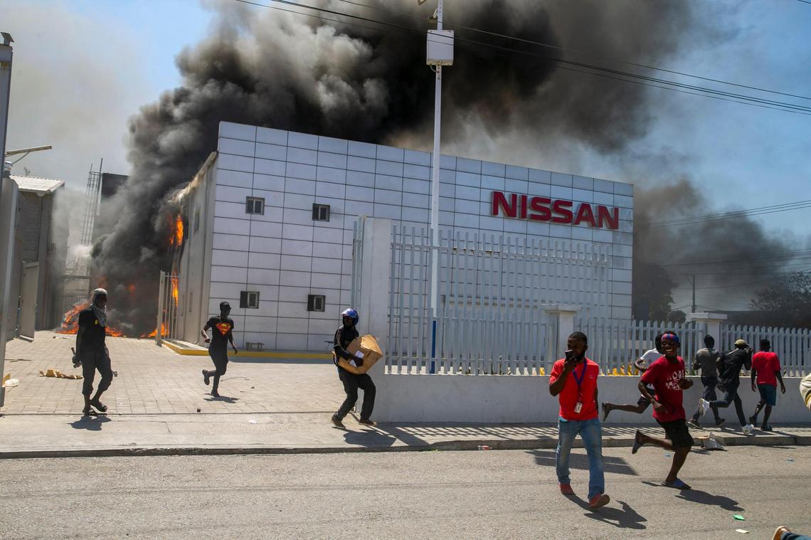 Looters flee from the Nissan auto dealership set ablaze during a protest in Port-au-Prince, Haiti, Wednesday, March 17, 2021.