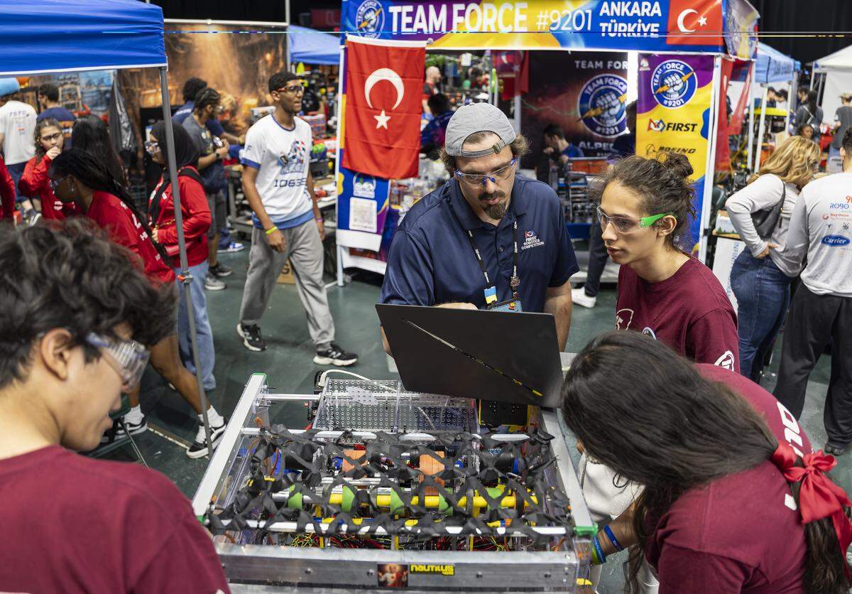 Student Andre Ronquillo, 17, far right, a member of Nautilus from Tecnológico de Monterrey in Mexico, troubleshoots his team’s robot, El Santo, as FIRST technical advisor Will Davies, center, assists before the team competes in the 2026 FIRST Robotics South Florida Regional Competition at the University of Miami’s Watsco Center on Friday, April 10, 2026, in Coral Gables, Fla. Participants from local school districts, surrounding states, and international teams are competing for an opportunity to earn a spot at the 2026 FIRST World Championship.