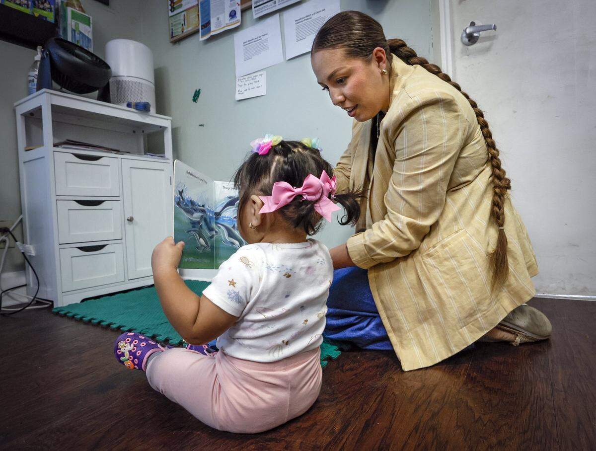 Mariana Blanco, director of operations, shows a children’s book to a child at the Guatemalan-Maya Center in Lake Worth, Florida, on Thursday, Nov. 6, 2025.