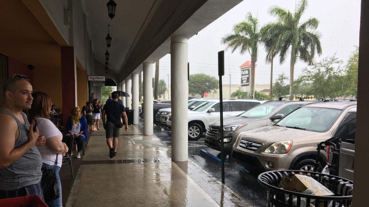 Storms had shoppers at a Doral strip mall seeking shelter in this Miami Herald photo from last summer. There’s a 60 percent chance of similar storms Sunday in Northwest Miami-Dade, Western Broward and all of Palm Beach.