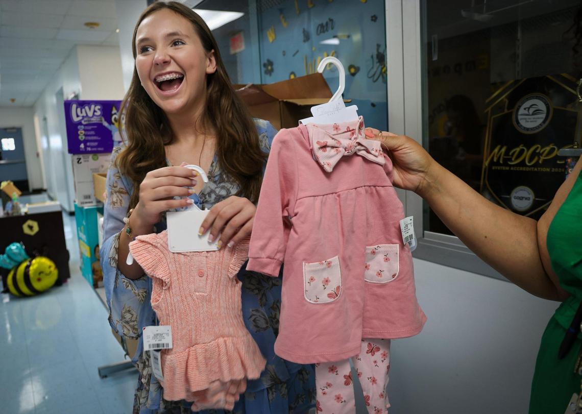 Mina Boomer shows pink dresses that were donated to the Dorothy M. Wallace Cope Center, a school for teen moms in Miami. Boomer delivered donated items such as diapers, bottles and other necessities for moms to the school to help the moms stock up for the summer.