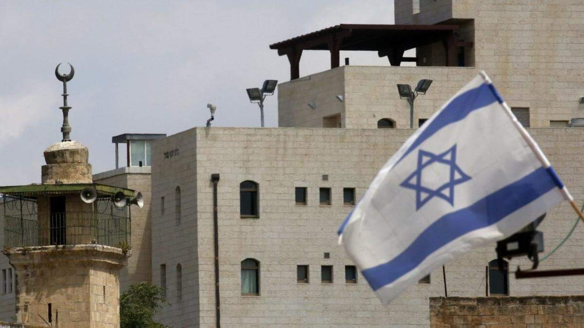 An Israeli flag flies near the minaret of a mosque at an Israeli settlement in the the old city of the West Bank town of Hebron.